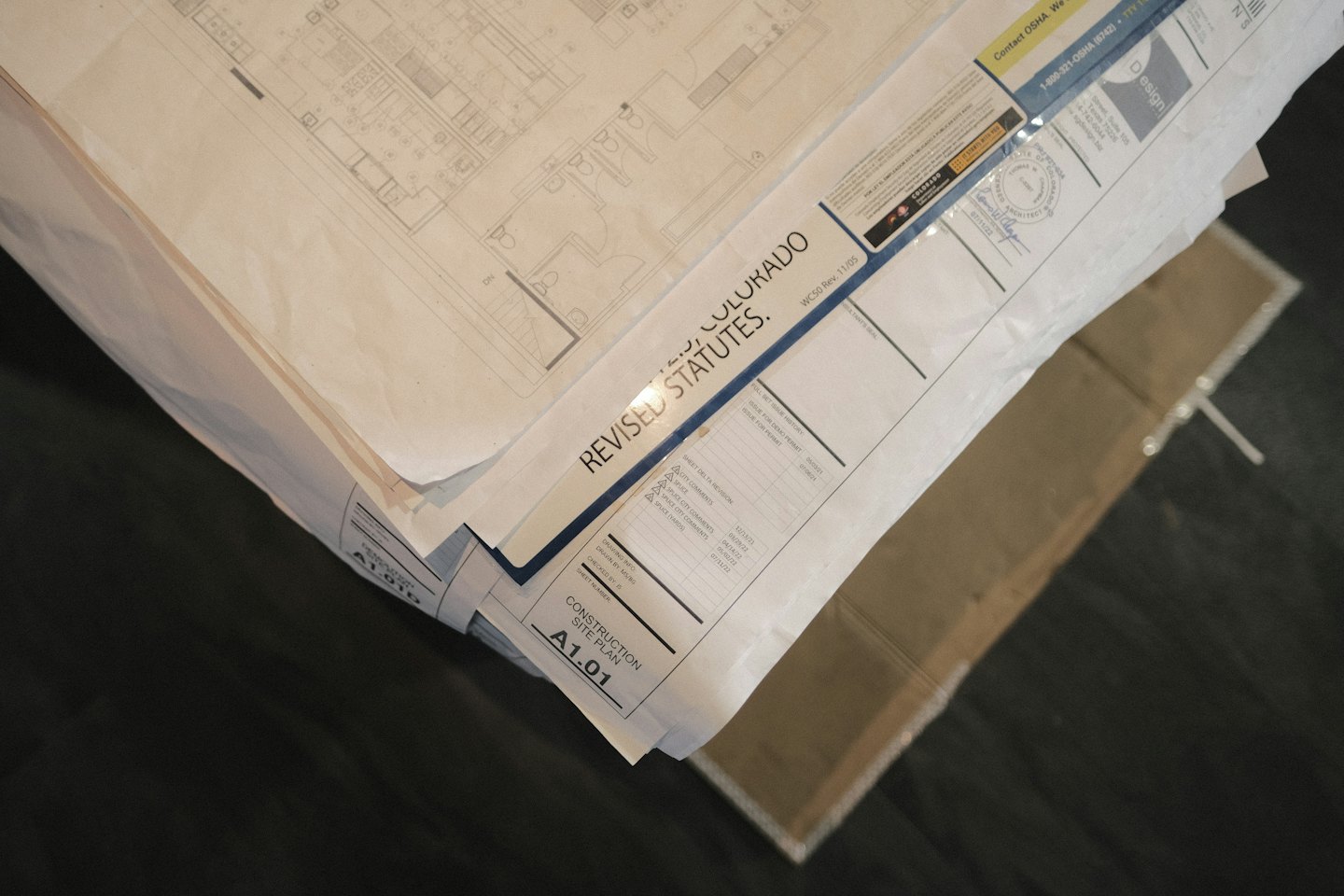Pila di progetti di costruzione architettonica con planimetrie e note.