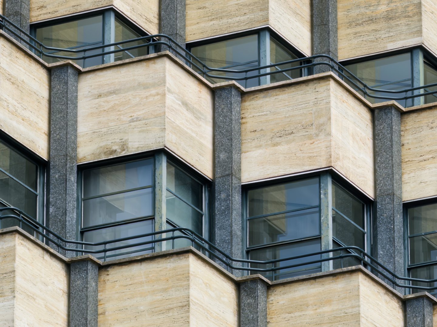 Facciata di un edificio moderno con balconi angolari e pilastri in pietra.