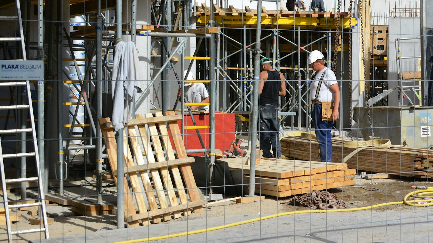 Due operai edili con elmetto lavorano in un cantiere attivo.